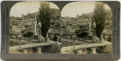 Carte stéréoscopique horizontale sépia montrant une vue de Sarajevo, Bosnie-Herzégovine. Au premier plan, un pont enjambe une rivière, et divers bâtiments sont visibles en arrière-plan. Numéro de stéréographe Keystone 15625. - Keystone View Company